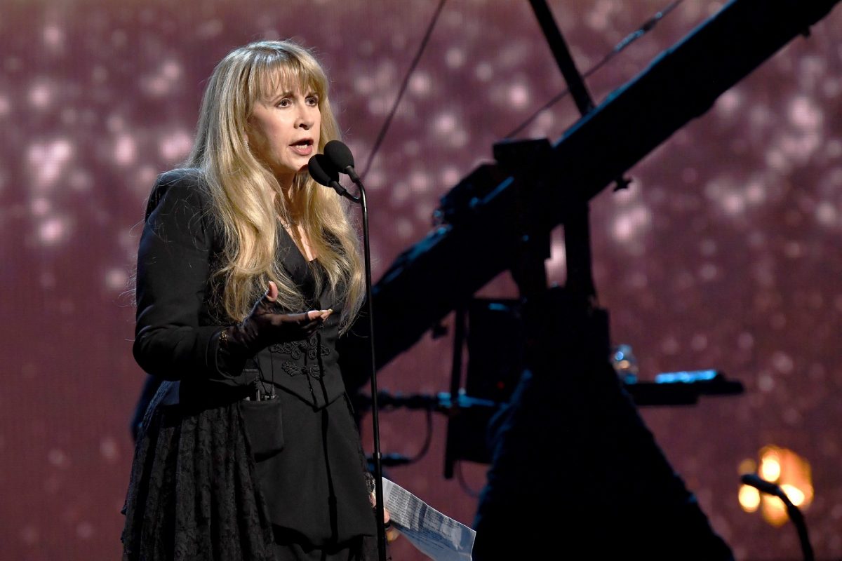 Stevie Nicks porte une longue tenue noire tout en parlant dans un microphone lors d'un concert.