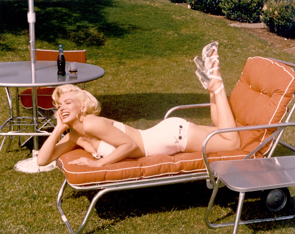 Marilyn Monroe, qui possédait une maison à Los Angeles, pose pour un portrait sur une chaise longue en maillot de bain et talons hauts