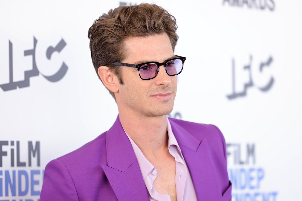 Andrew Garfield souriant tout en portant une tenue violette.