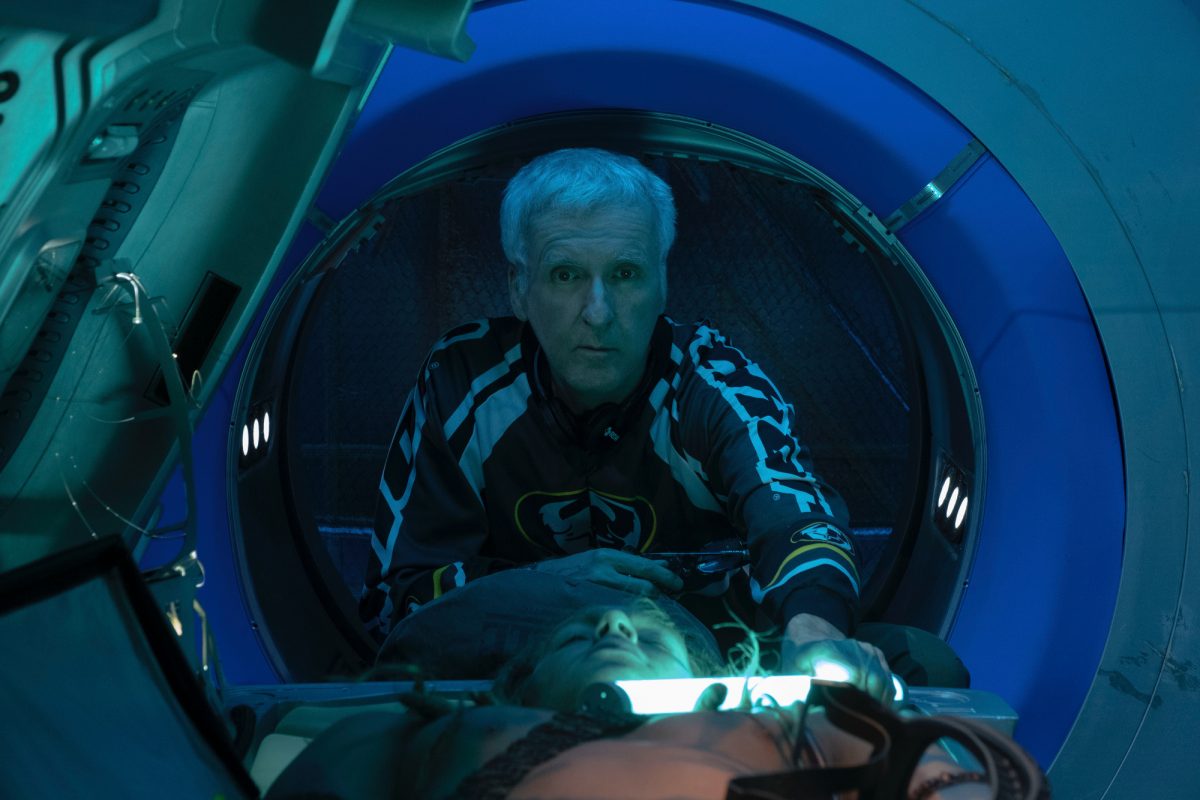 'Avatar 2' James Cameron dans les coulisses penché en avant tenant un tube lumineux au-dessus d'un corps