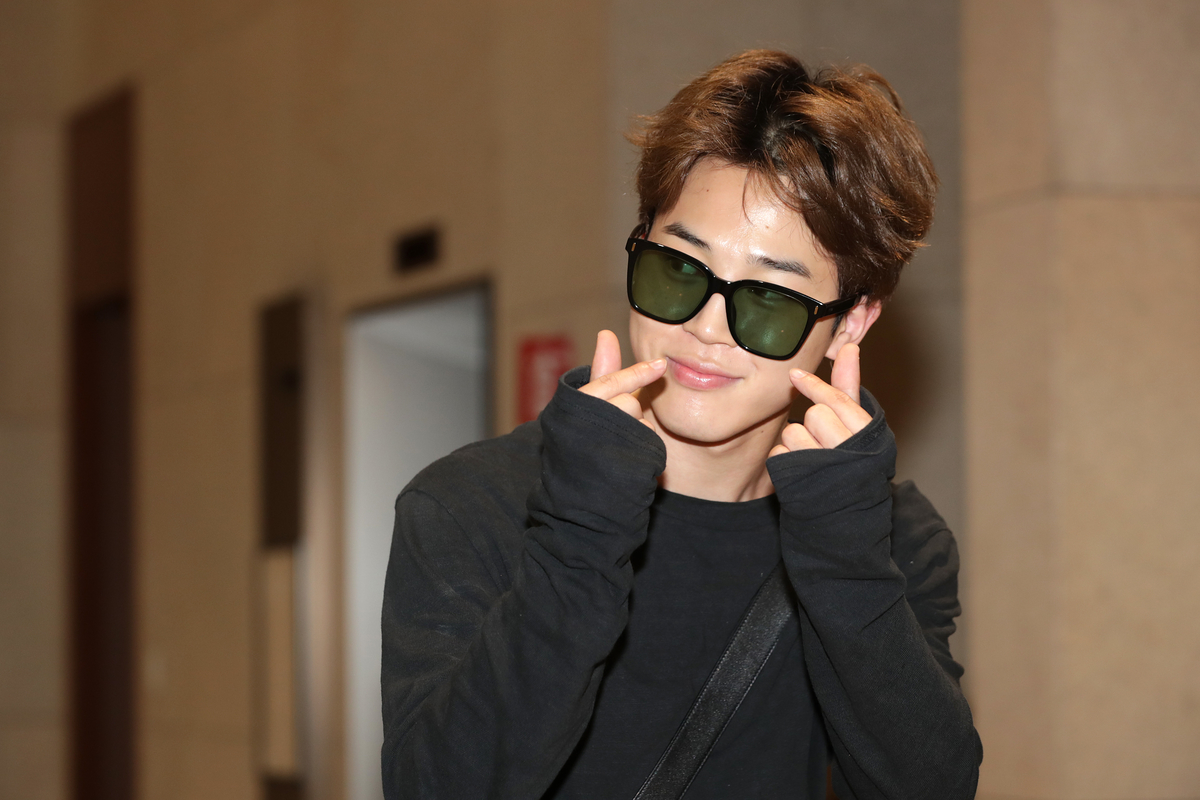 Jimin, membre du BTS, tient le cœur des doigts à son arrivée à l'aéroport de Gimpo à Séoul, en Corée du Sud.