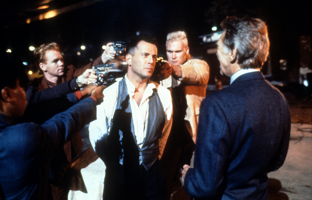 David Caruso tient une arme à Bruce Willis alors que James Coburn regarde dans