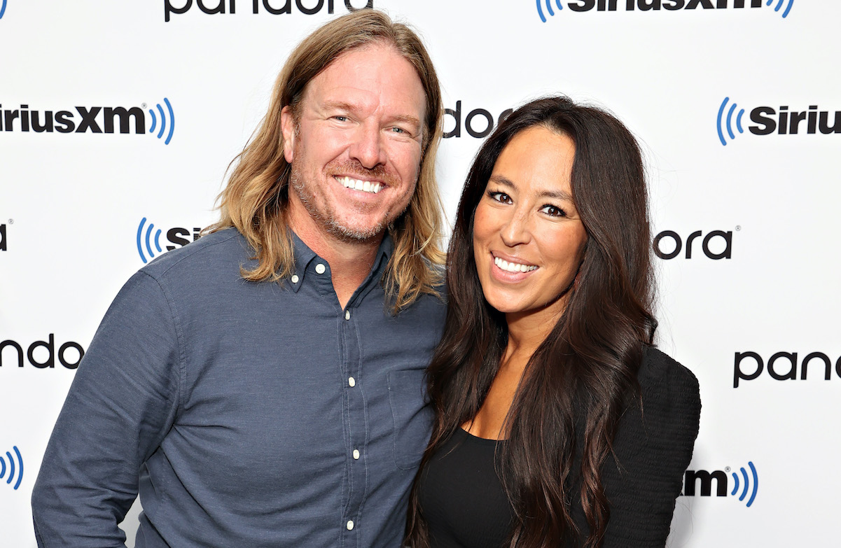 Chip Gaines sourit et pose aux côtés de Joanna Gaines vêtue de noir et souriante