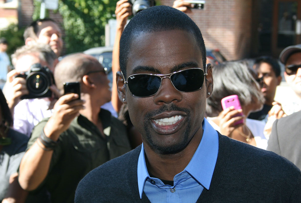 Chris Rock porte des lunettes de soleil sur le tapis rouge sous le regard des fans