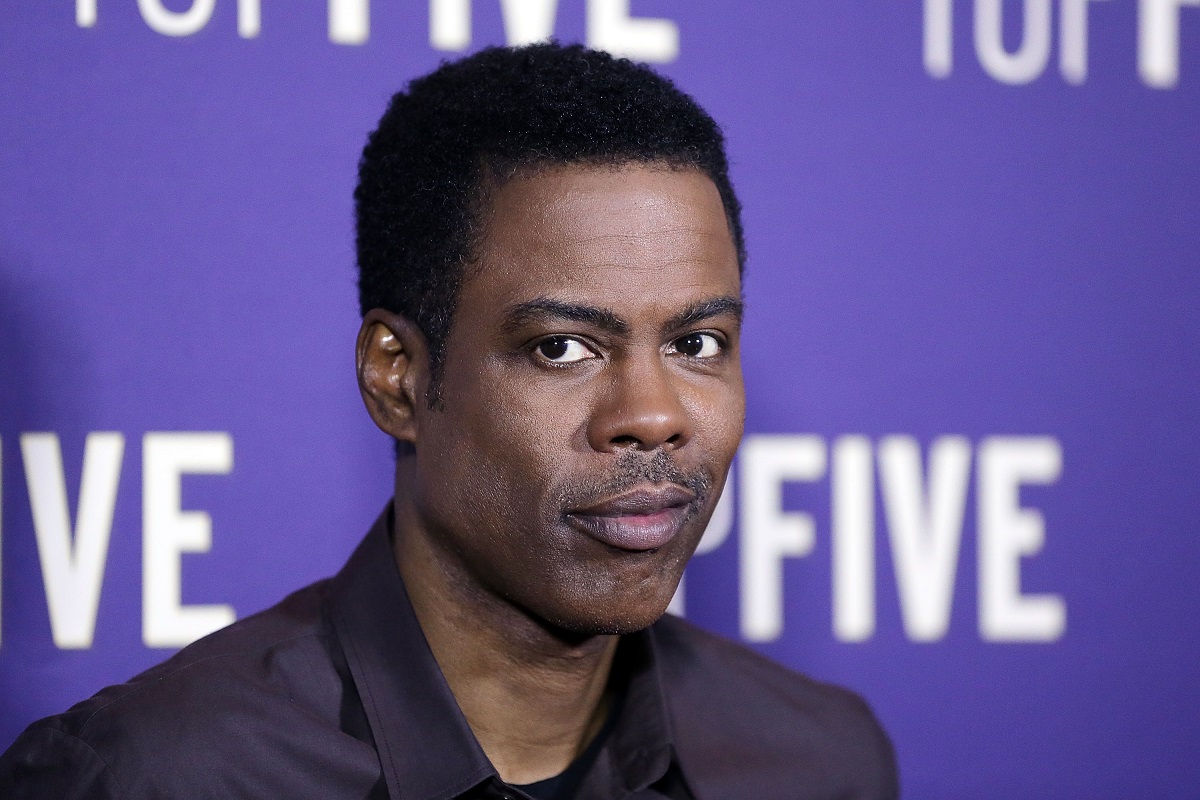 Chris Rock sourit en portant une veste.