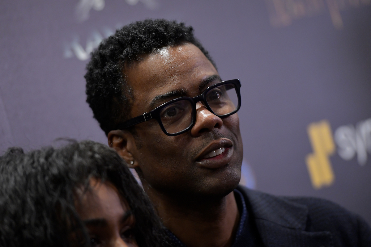 Chris Rock porte des lunettes et pose sur le tapis rouge