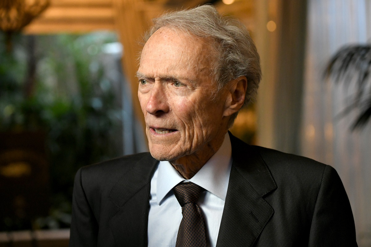 Clint Eastwood regarde sur le côté tout en portant un costume d'affaires.