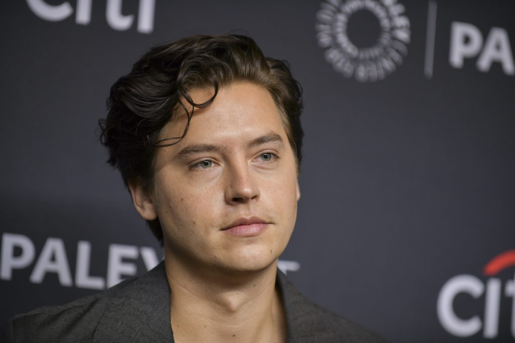 Cole Sprouse devant un fond gris