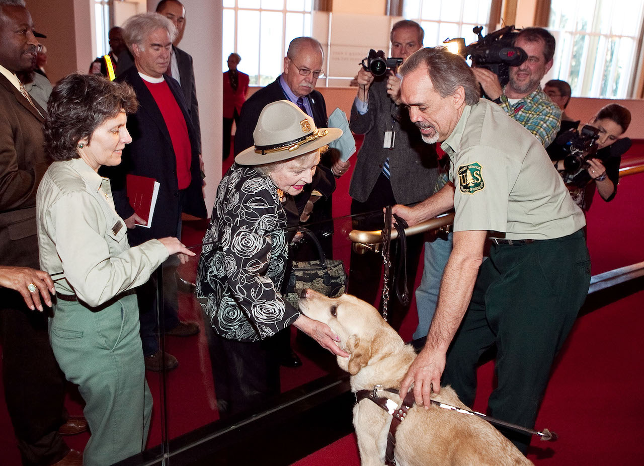 Betty White (au centre) portant un chapeau de garde forestier et caressant un chien jaune