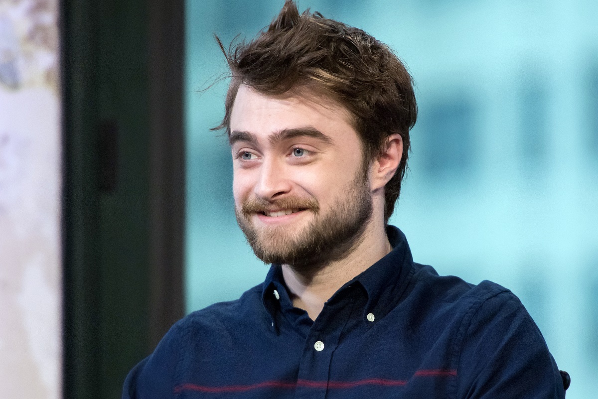 Daniel Radcliffe souriant tout en portant une chemise bleue.