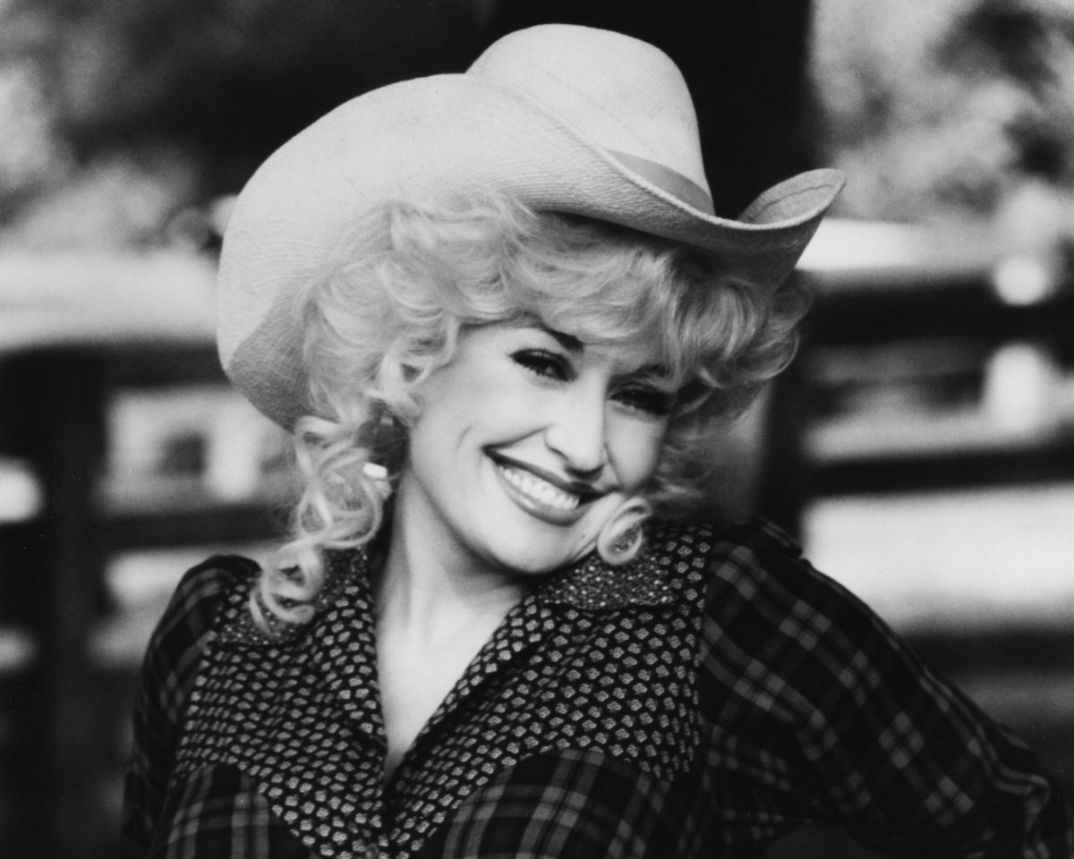 Une photo en noir et blanc de Dolly Parton portant un chapeau de cowboy. 