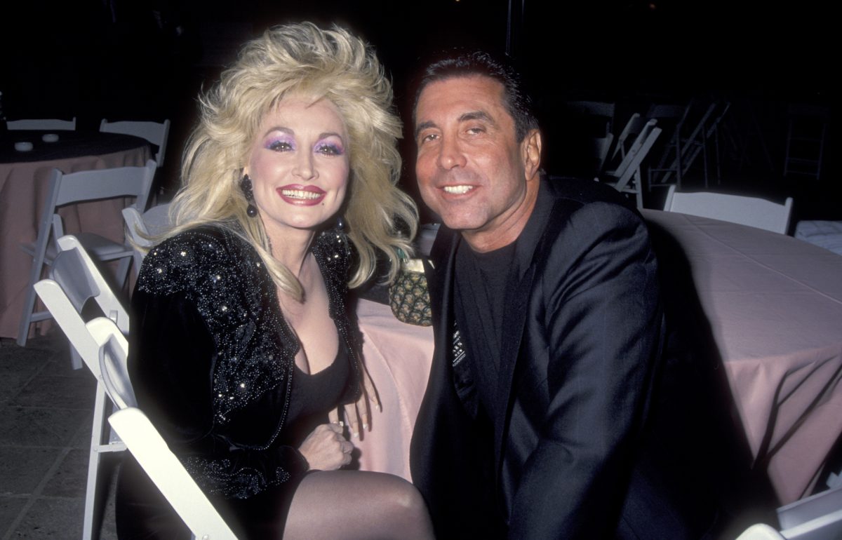 Dolly Parton et sa manager Sandy Gallin portent du noir et sont assises à une table ronde avec une nappe rose. 