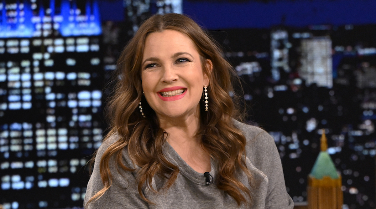 Drew Barrymore sourit et regarde porter une chemise grise