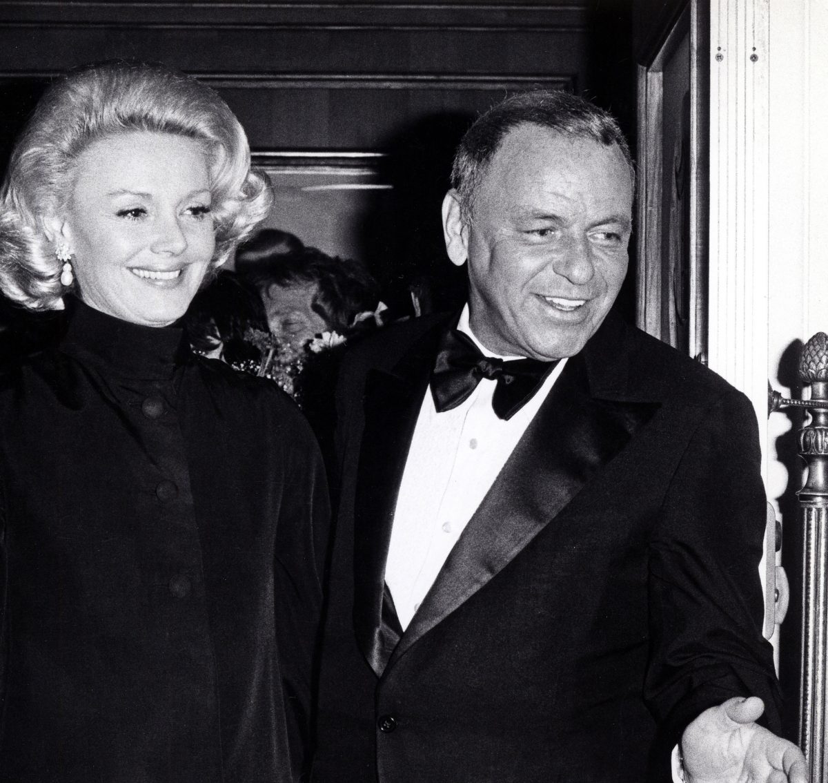 Une photo en noir et blanc de Frank Sinatra et de sa femme Barbara Sinatra quittant les Oscars.  Ils sourient tous les deux.