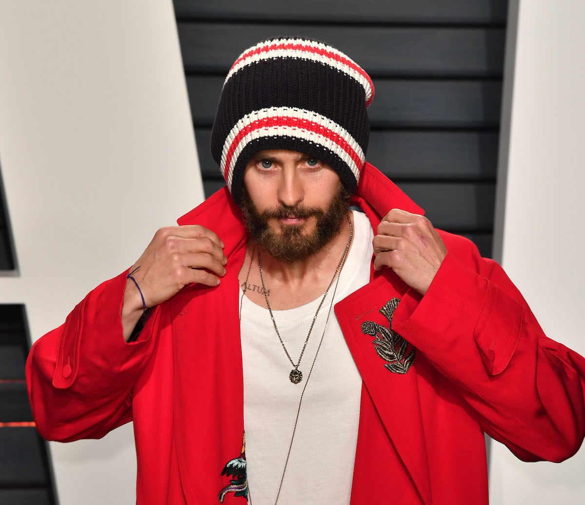 Jared Leto pose avec un chapeau et une veste rouge