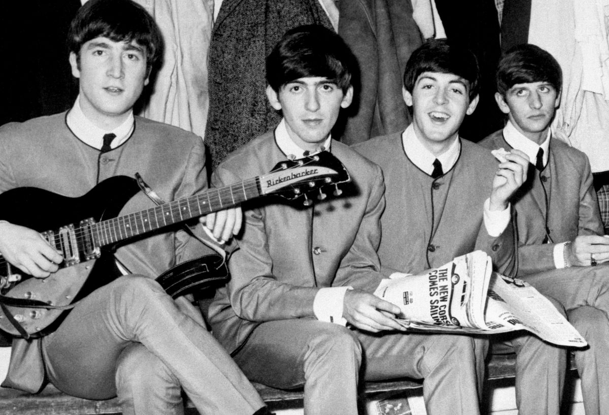 John Lennon, George Harrison, Paul McCartney et Ringo Starr des Beatles assis sur un banc