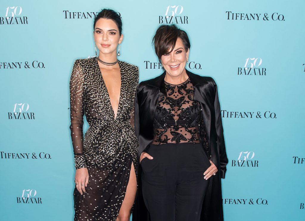 Kendall Jenner et Kris Jenner portant des tenues noires et debout devant un fond bleu sarcelle