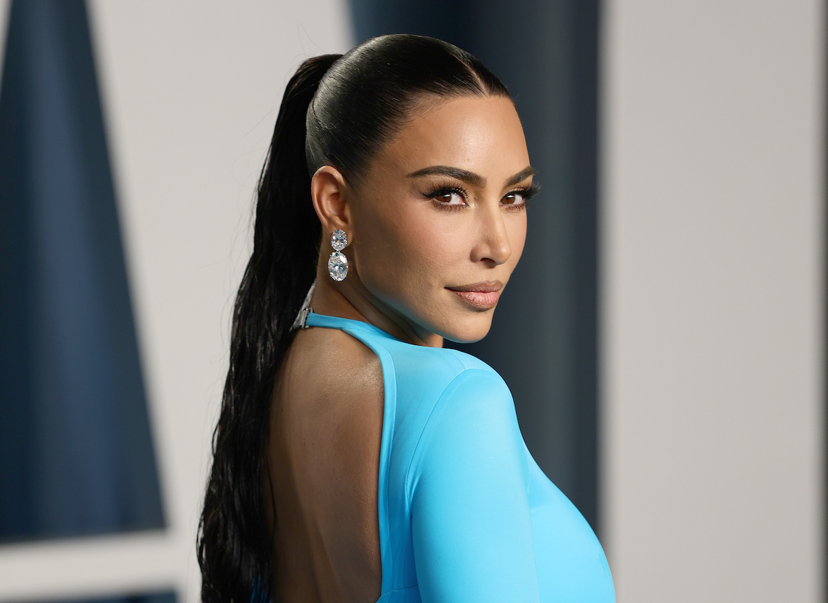 Kim Kardashian sourit et porte une robe bleu vif lors d'un événement.