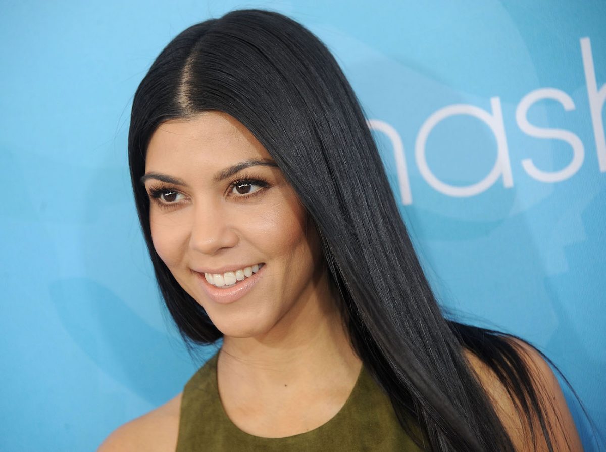 Kourtney Kardashian regarde tout en souriant et portant une tenue verte