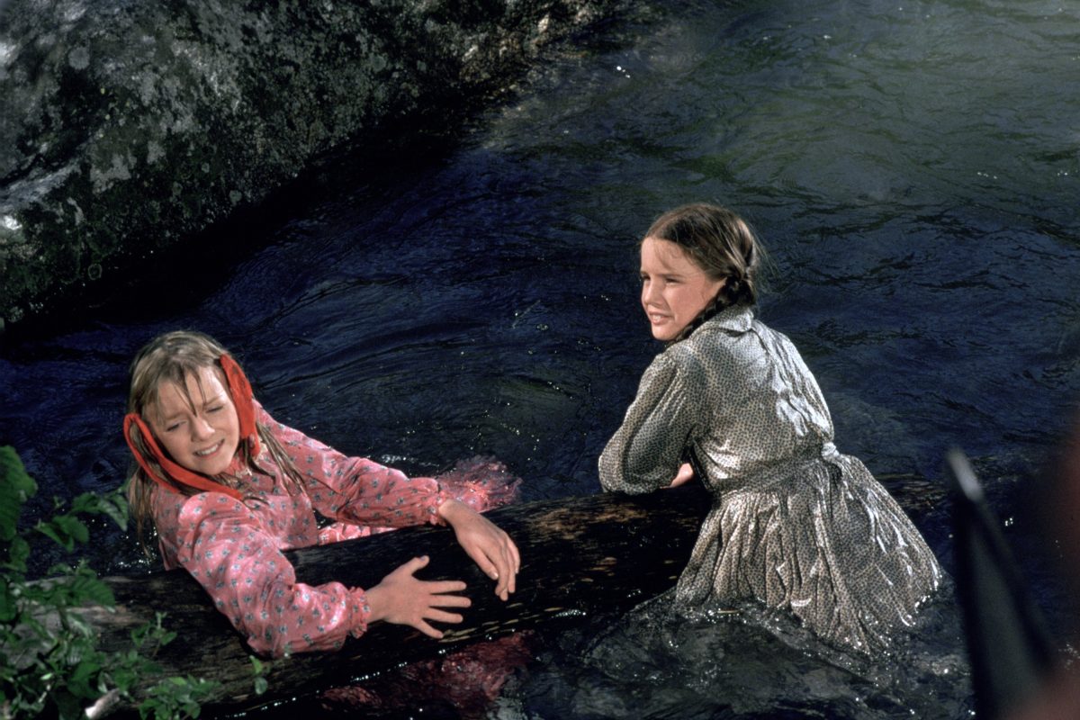Alison Arngrim et Melissa Gilbert tiennent une bûche en attendant dans l'eau sur le tournage de La petite maison dans la prairie.