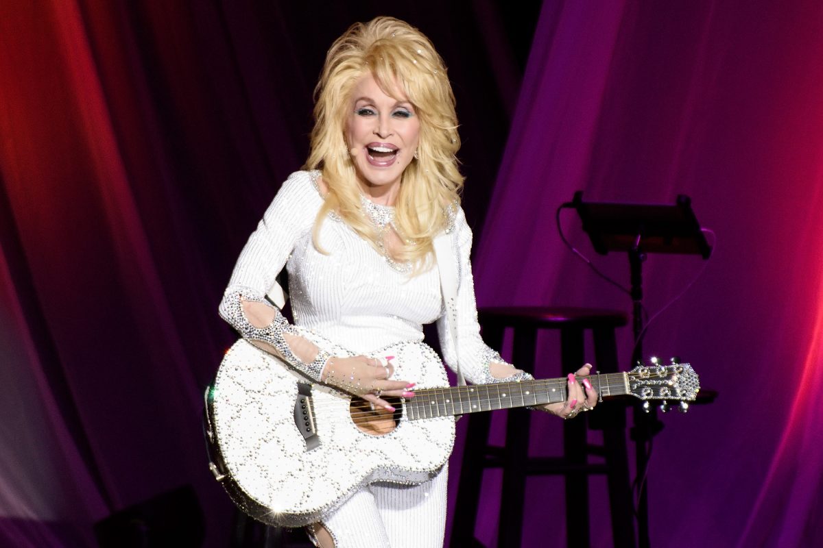Dolly Parton porte une tenue entièrement blanche et gratte une guitare blanche.