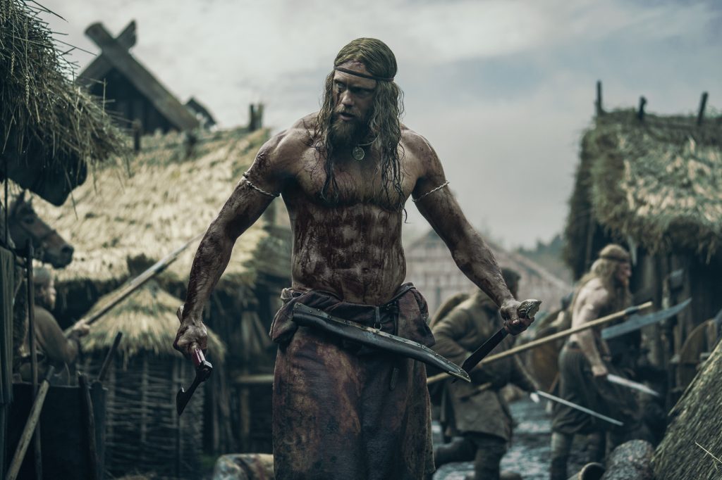 'The Northman' Alexander Skarsgård dans le rôle d'Amleth torse nu couvert de sang tenant une arme dans chaque main
