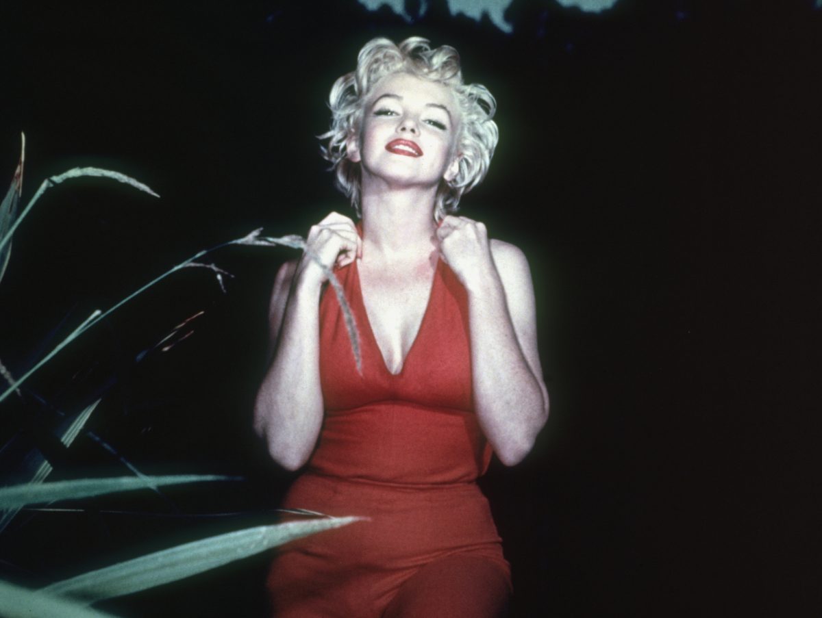 Marilyn Monroe, le sujet du biopic 'Blonde' dans une robe rouge souriante avec son menton haut