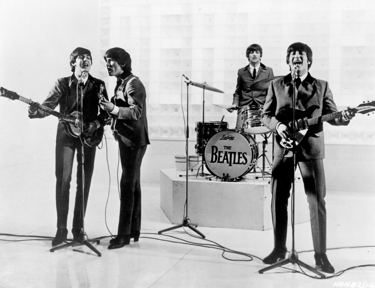 Paul McCartney, George Harrison, Ringo Starr et John Lennon des Beatles près d'une batterie