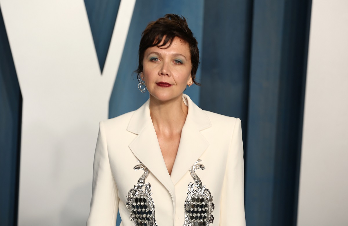 Maggie Gyllenhaal sourit en portant une robe blanche.