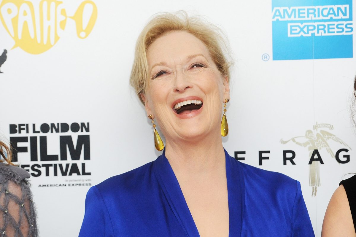 L'actrice oscarisée Meryl Streep vêtue de bleu et riant devant un pas et une répétition