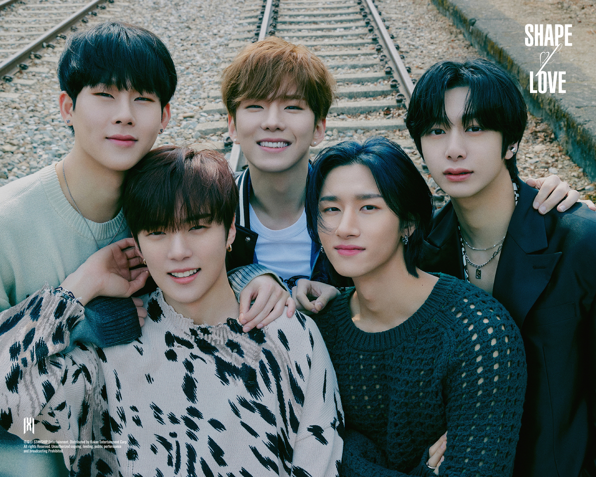 Monsta X pose devant la pochette de l'album