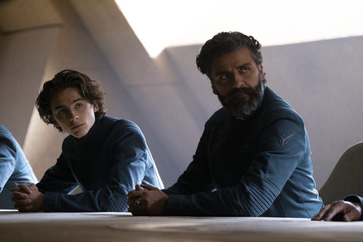 'Dune' Timothée Chalamet dans le rôle de Paul Atreides et Oscar Isaac dans le rôle du duc Leto Atreides assis l'un à côté de l'autre dans des costumes identiques, les mains jointes sur la table