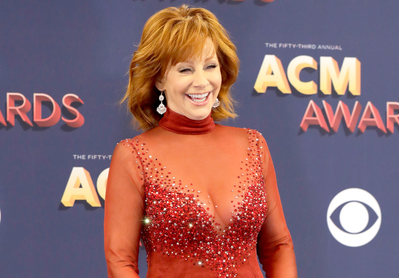 Reba McEntire rit et pose pour une photo dans sa robe rouge des '93 CMA Awards en 2018