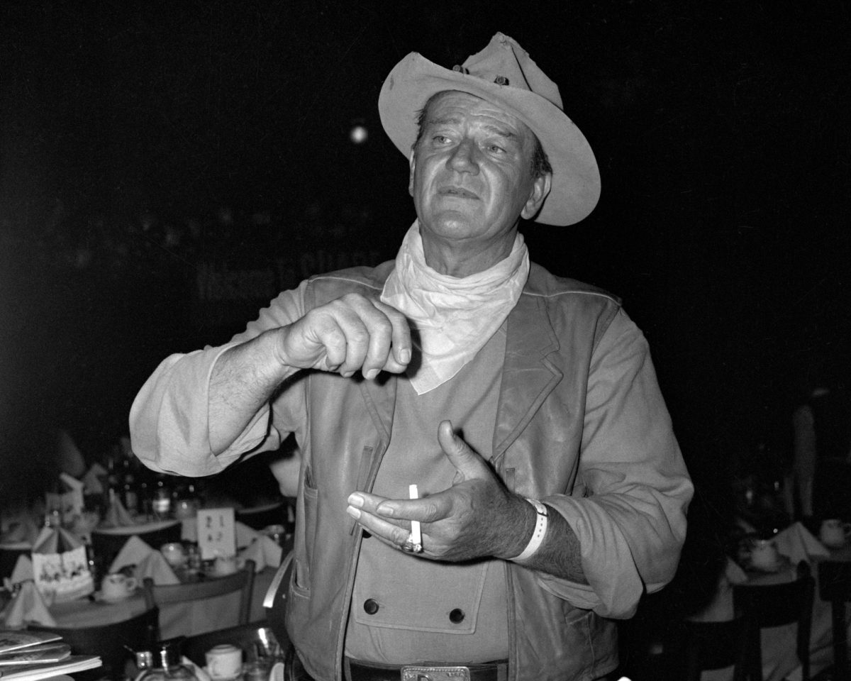 John Wayne, qui a soumis la recette de John Wayne Casserole, portant un chapeau de cow-boy et tenant une cigarette lors d'un dîner inconnu
