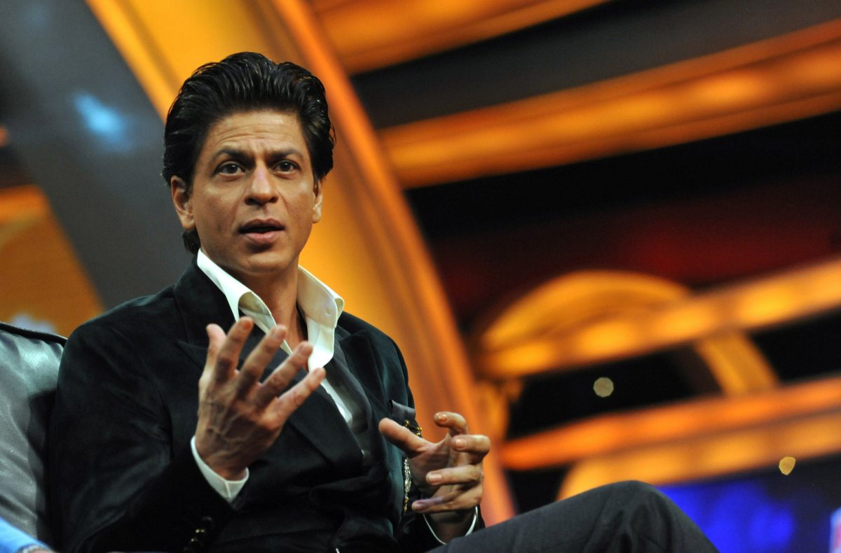 L'acteur de cinéma Shah Rukh Khan portant un costume et utilisant ses mains pour parler