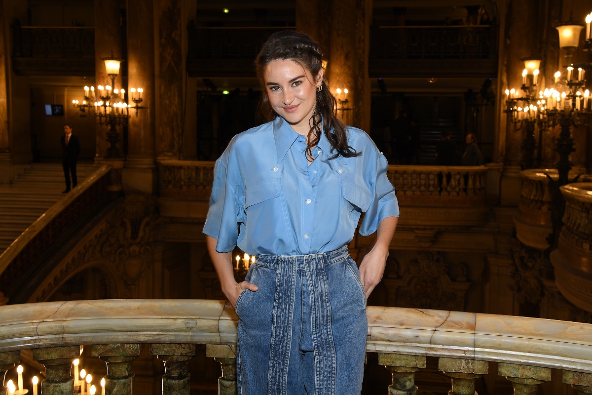 Shailene Woodley sourit en portant des vêtements bleus.