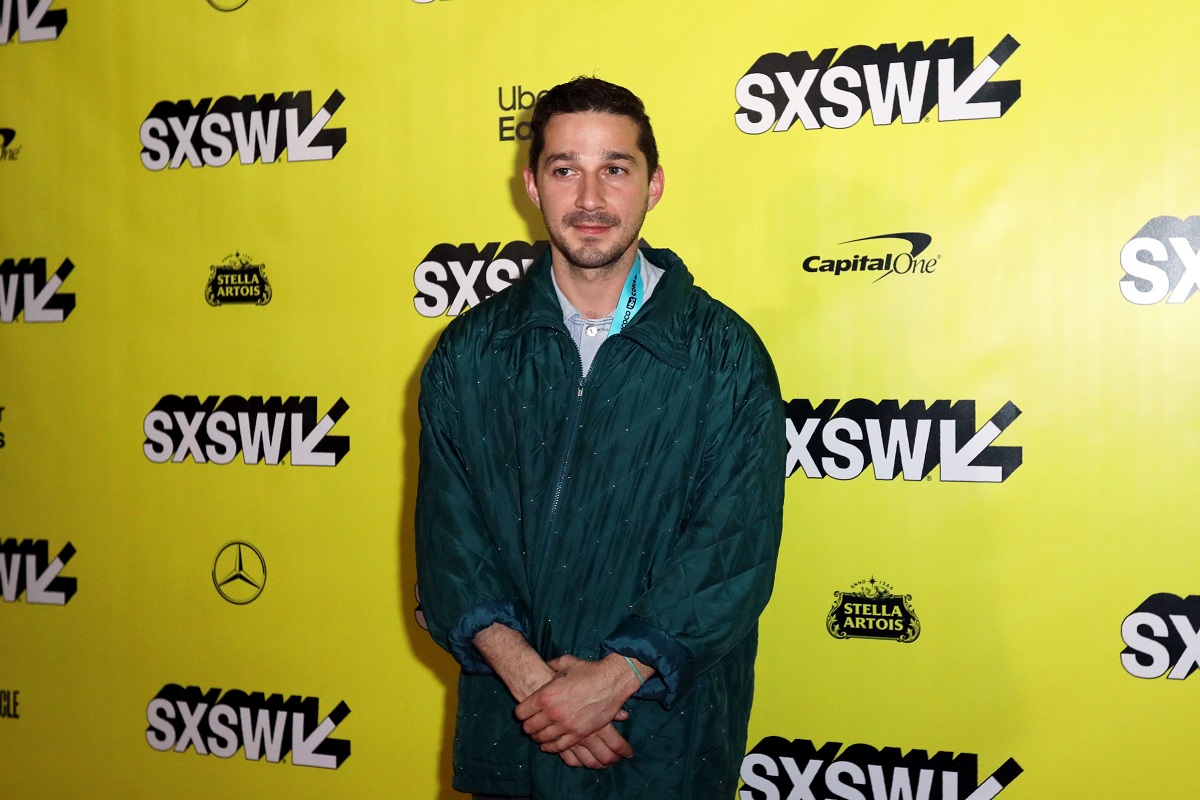 Shia LaBeouf sourit en portant une veste.