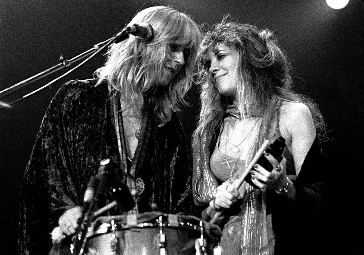 Une photo en noir et blanc de Christine McVie et Stevie Nicks. McVie se tient devant un tambour et Nicks tient une sonnaille.