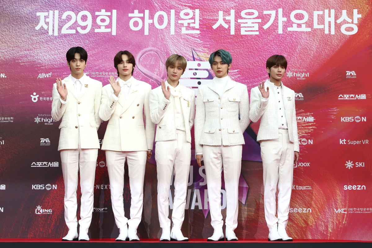 Vêtus de costumes blancs, les membres de TOMORROW X TOGETHER posent sur le tapis rouge des Seoul Music Awards à Séoul, en Corée du Sud.