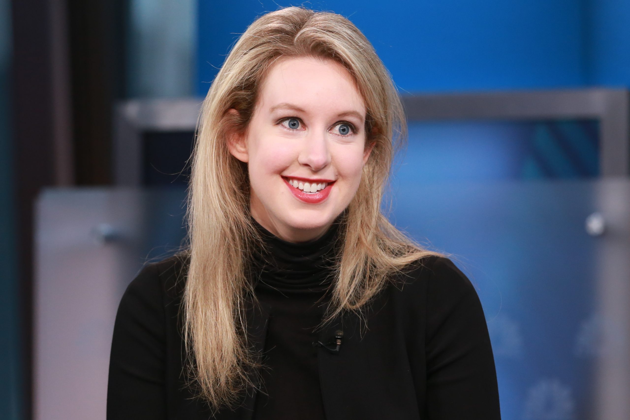 Elizabeth Holmes souriante dans un col roulé noir