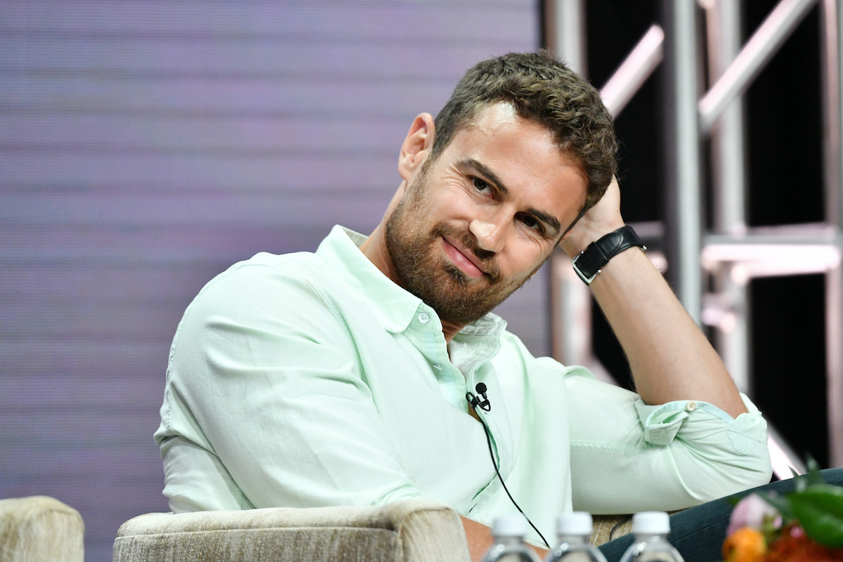 Theo James sourit en portant une chemise verte