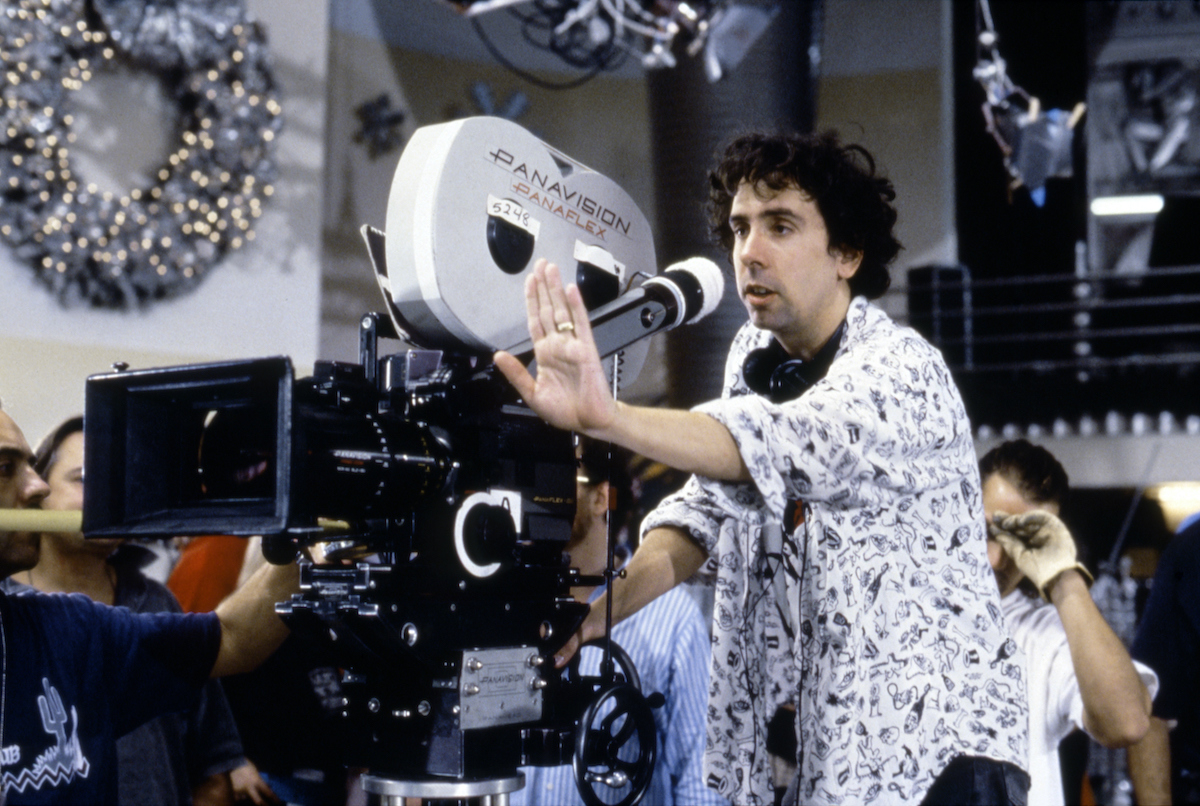 Tim Burton se tient derrière une caméra avec sa main tendue sur le tournage de