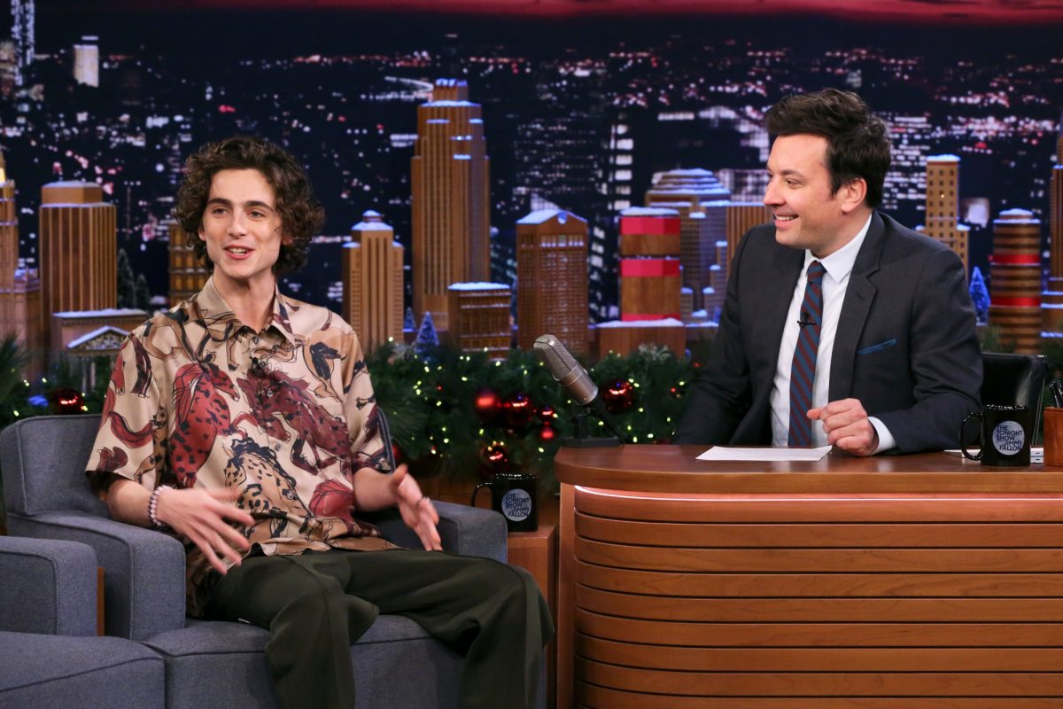 Timothée Chalamet et Jimmy Fallon sur 'The Tonight Show' avant de montrer son talent caché sur scène avec Jimmy derrière son bureau vêtu d'un costume et Timothée assis sur une chaise de canapé en souriant