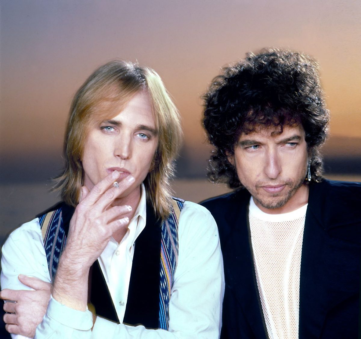 Tom Petty porte une chemise blanche et un gilet et fume une cigarette. Bob Dylan porte une chemise blanche et un gilet noir.