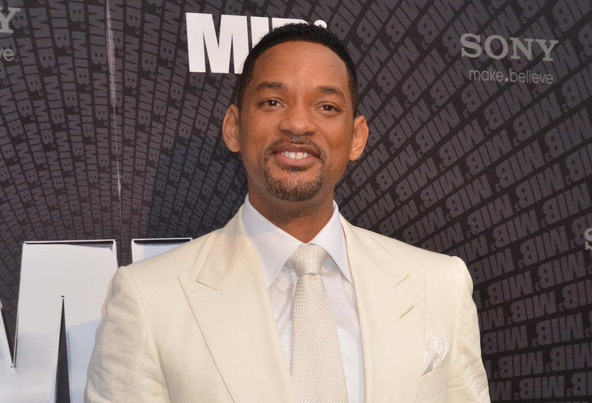 Will Smith porte un costume et pose devant le logo 'Men In Black 3'
