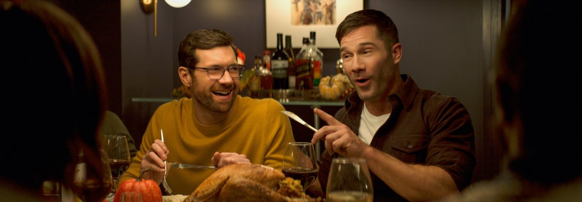 'Bros' Billy Eichner dans le rôle de Bobby et Luke Macfarlane dans le rôle d'Aaron souriant, tenant des ustensiles de table avec de la nourriture devant eux