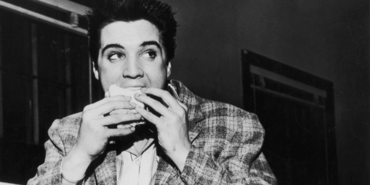 Une photo en noir et blanc d'Elvis Presley en train de manger prise en 1958.