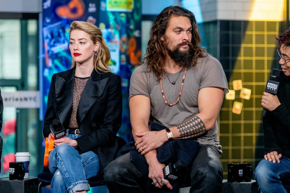 'Aquaman' Amber Heard et Jason Momoa sont assis tenant des microphones regardant dans des directions opposées assis l'un à côté de l'autre