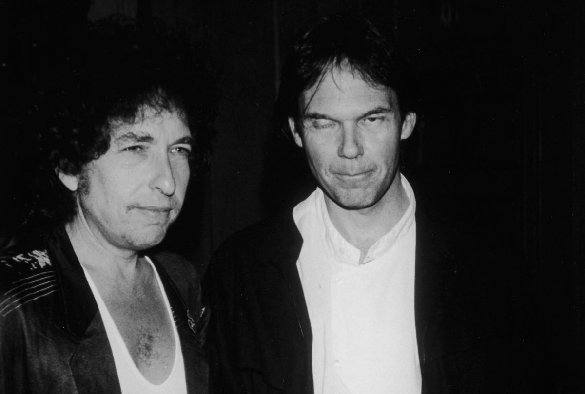 Une photo en noir et blanc de Bob Dylan et Neil Young portant tous deux des chemises blanches et des vestes noires.