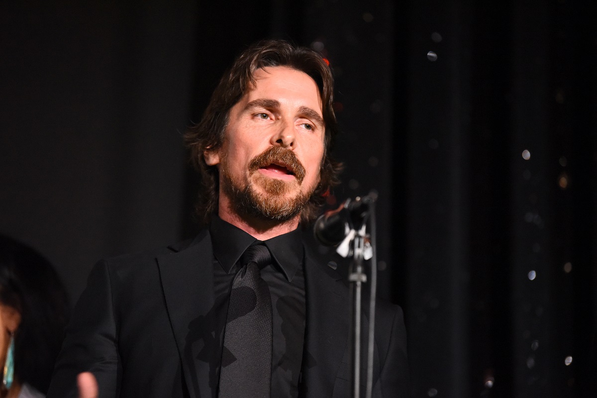 Christian Bale s'exprimant sur scène tout en portant un costume tout noir.